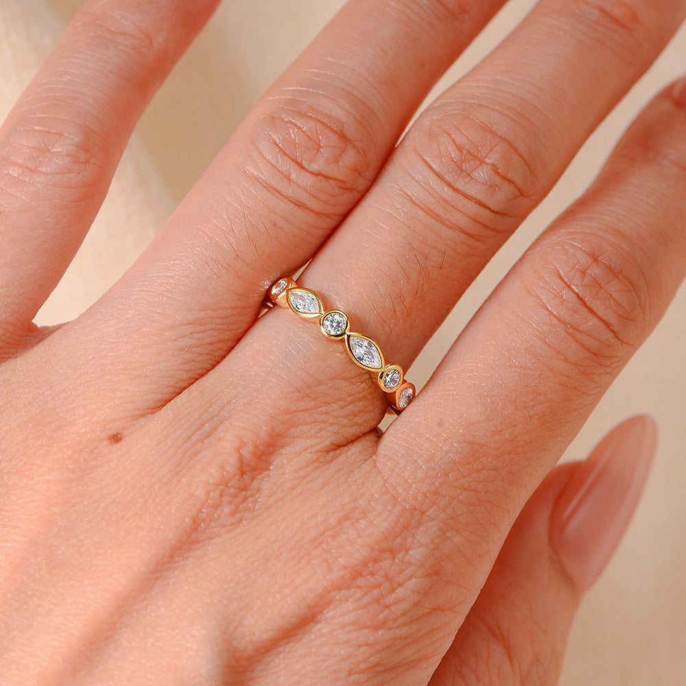 Gold eternity ring with alternating marquise and round crystals, shown worn on a finger to display scale and design.