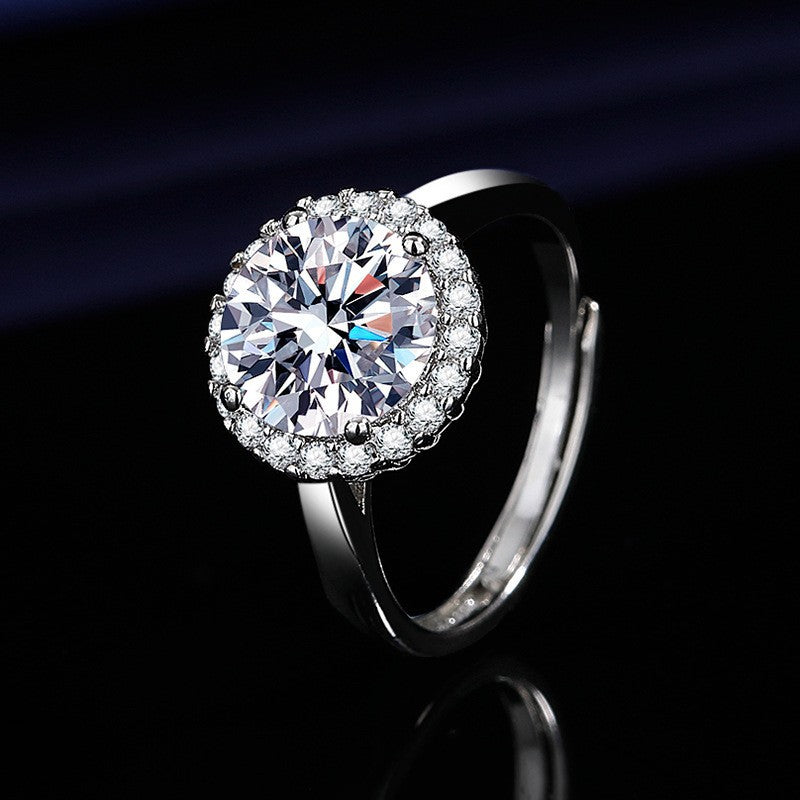 Silver halo engagement ring with a large brilliant-cut center crystal surrounded by a cluster of smaller sparkling stones on a dark background.