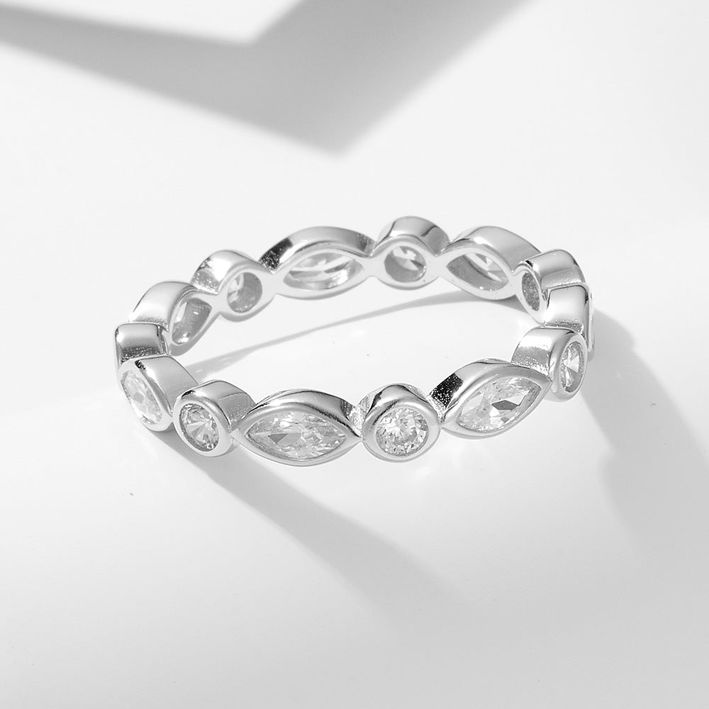 Silver eternity ring with alternating marquise and round-cut crystals in a bezel setting, displayed on a white surface.
