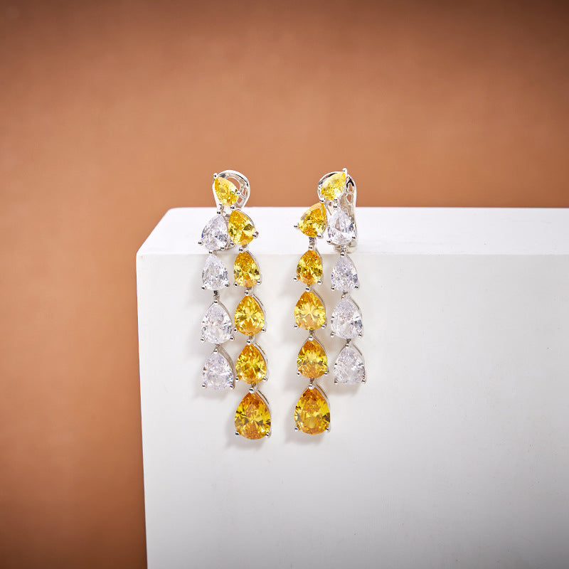Elegant silver chandelier earrings featuring a cascading design of yellow and white teardrop-shaped crystals.