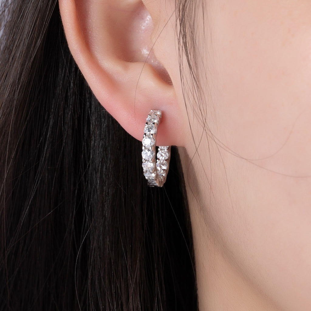 Silver hoop earring lined with sparkling round-cut crystals, shown worn on a person's ear to demonstrate fit.