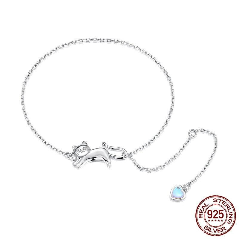 Silver chain bracelet featuring a cute cat-shaped charm and a small heart-shaped pendant on a light blue background.