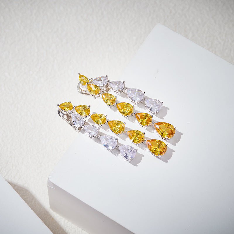 Top-down view of yellow and white cascading crystal earrings laid flat on a white surface.