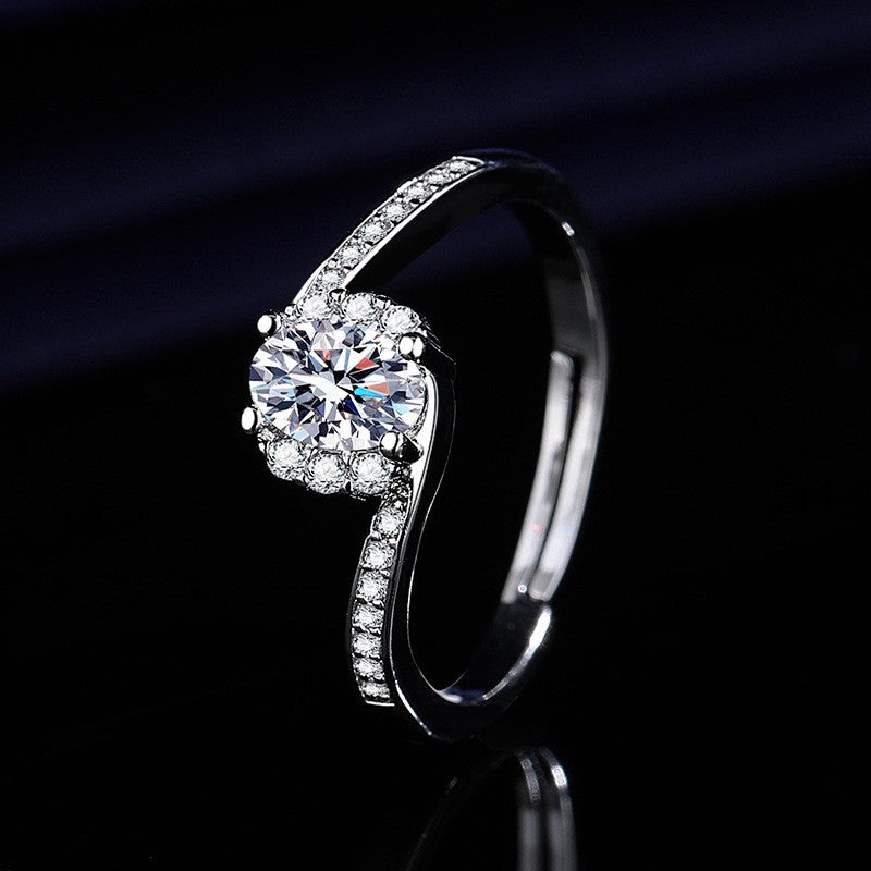 Silver halo engagement ring with a large brilliant-cut center crystal surrounded by a cluster of smaller sparkling stones on a dark background.
